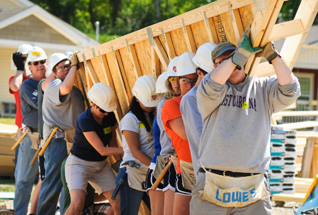 A team of workers constructing a house with a wooden frame.